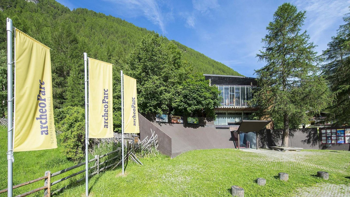 Das ArcheoParc Besucherzentrum, eingebettet in die üppige Natur Südtirols, begrüßt seine Gäste mit wehenden Fahnen und lädt zu einer Reise in die Vergangenheit ein.
