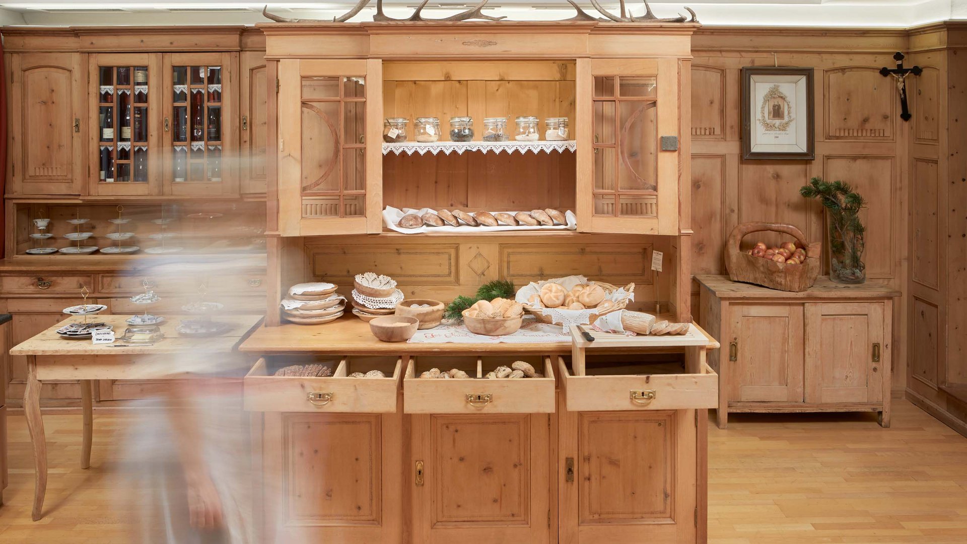 Rustikales Frühstücksbuffet im Hotel Bella Vista mit einer Auswahl an lokalen Spezialitäten, präsentiert in einer traditionell gestalteten Holzküche.